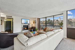 Carpeted living room featuring a fireplace, floor to ceiling natural light and walk out to two balcony areas with views