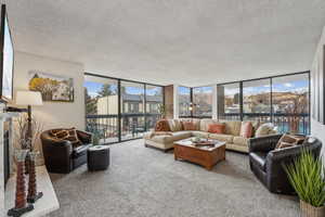 Carpeted living room featuring a fireplace, floor to ceiling natural light and walk out to two balcony areas with views