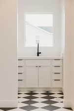 Bar featuring a healthy amount of sunlight, sink, and white cabinets