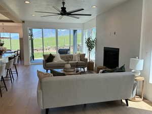 Living room featuring ceiling fan, a mountain view, a textured ceiling, and light hardwood / wood-style flooring