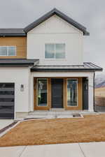 View of front of home with a garage, a front lawn, and covered porch