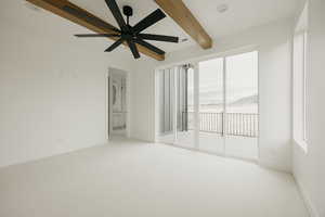 Carpeted empty room with ceiling fan and beam ceiling