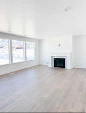 Unfurnished living room with a tile fireplace, a textured ceiling, and light wood-type flooring