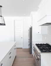 Kitchen featuring white cabinetry, decorative light fixtures, light hardwood / wood-style floors, and premium appliances