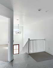 Staircase featuring a chandelier, carpet floors, and a textured ceiling