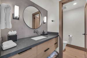 Bathroom with wood-type flooring, toilet, vanity, and backsplash