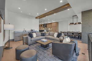 Living room featuring sink, a notable chandelier, light hardwood / wood-style floors, and wood walls