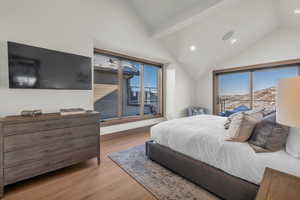 Bedroom featuring access to exterior, a mountain view, light wood-type flooring, and vaulted ceiling with beams