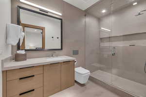 Bathroom featuring vanity, a shower with shower door, tile walls, and toilet