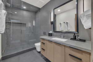 Bathroom featuring tile patterned flooring, vanity, a shower with shower door, and toilet