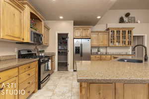 Kitchen featuring sink, stainless steel appliances, a textured ceiling, light tile patterned flooring, and light brown cabinets