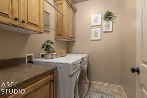 Laundry area with cabinets, light tile patterned flooring, and separate washer and dryer