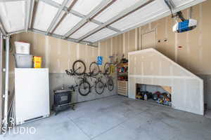 Garage featuring a garage door opener and refrigerator