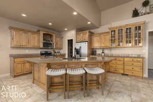 Kitchen featuring appliances with stainless steel finishes, a kitchen island with sink, and a breakfast bar