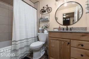 Full bathroom featuring vanity, toilet, and shower / bathtub combination with curtain