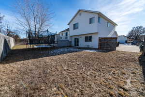 Rear view of house featuring a trampoline and a deck