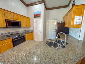 Kitchen featuring a towering ceiling, appliances with stainless steel finishes, sink, and decorative backsplash