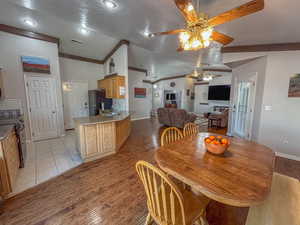 Dining space featuring vaulted ceiling, sink, light wood-type flooring, ceiling fan, and a textured ceiling