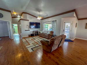 Living room featuring hardwood / wood-style floors, vaulted ceiling, and ceiling fan