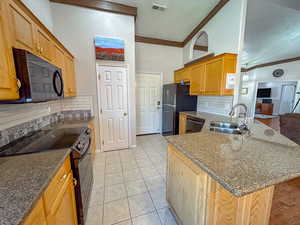 Kitchen featuring light tile patterned flooring, high vaulted ceiling, tasteful backsplash, sink, and black appliances