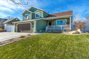 View of front of home with a garage, a front yard, and covered porch