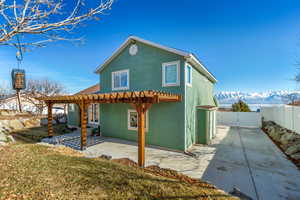 Rear view of house featuring a mountain view, a pergola, a patio area, and a lawn