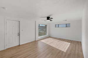 Interior space with ceiling fan, light hardwood / wood-style floors, and a textured ceiling