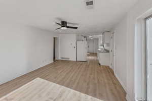 Unfurnished living room featuring ceiling fan and light wood-type flooring