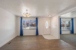 Entryway with hardwood flooring and a notable chandelier