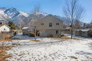 Snow covered back of property featuring a mountain view and a storage unit