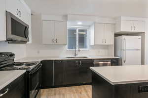 Kitchen featuring stainless steel appliances, white cabinetry, sink, and light wood-type flooring