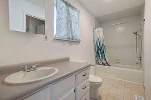 Full bathroom featuring shower / bath combination with curtain, vanity, and toilet