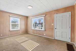 Empty room with light colored carpet and wood walls