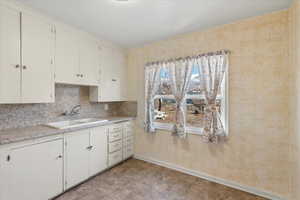 Kitchen with white cabinetry, sink, and backsplash