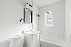 Full bathroom featuring vanity, toilet, and tiled shower / bath combo