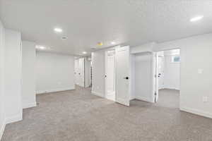 Basement with light carpet and a textured ceiling