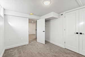 Unfurnished bedroom with a closet, light carpet, and a textured ceiling