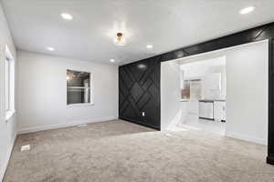 Unfurnished room featuring light colored carpet and a textured ceiling