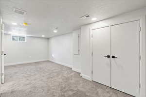 Basement with light carpet and a textured ceiling