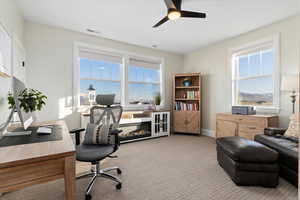 Carpeted home office featuring a mountain view and ceiling fan