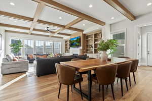 Dining room featuring beamed ceiling, coffered ceiling, built in features, and light wood-type flooring