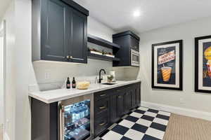 Bar featuring stainless steel microwave, sink, and beverage cooler