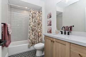 Full en suite bathroom with vanity, tile patterned floors, toilet, and shower / bath combo