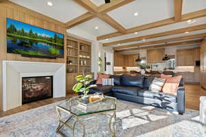 Living room featuring beam ceiling, built in shelves, and light hardwood / wood-style floors