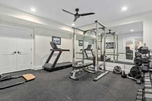 Interior space with ceiling fan and gym floors with mirrored walls