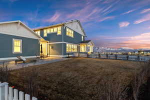 Back house at dusk with a patio, a mountain view, and a yard