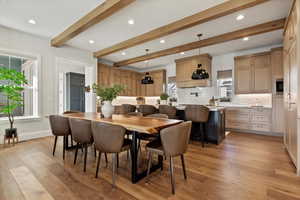 Dining space with light hardwood / wood-style floors and beamed ceiling