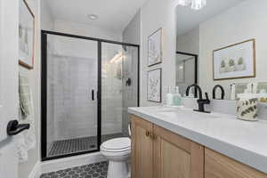 Bathroom with walk in shower, tile patterned floors, toilet, and vanity