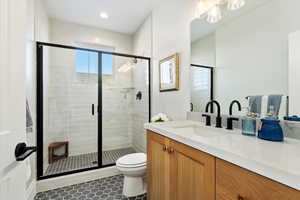 Bathroom featuring vanity, a shower with shower door, tile patterned floors, and toilet