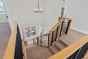 Stairway with a notable chandelier and carpet floors